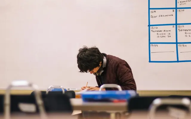 A student writing a test in a classroom